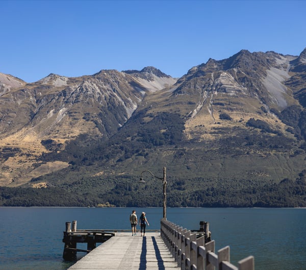 People standing on a wharf at a lake on a sunny day.
