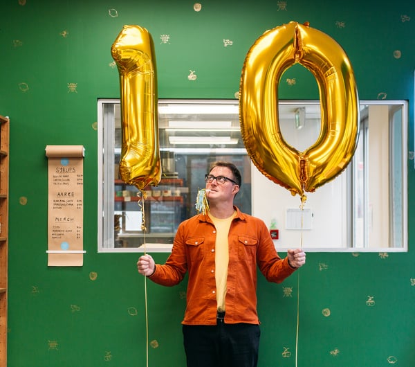 Joe Slatter holding two gold ballons with the numbers 1-0.