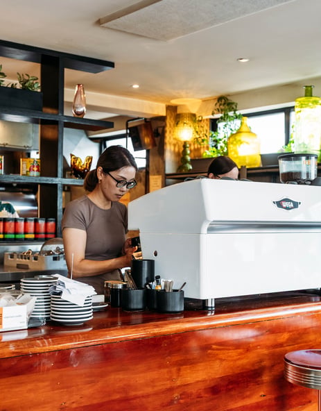 A woman making coffee at a coffee machine.