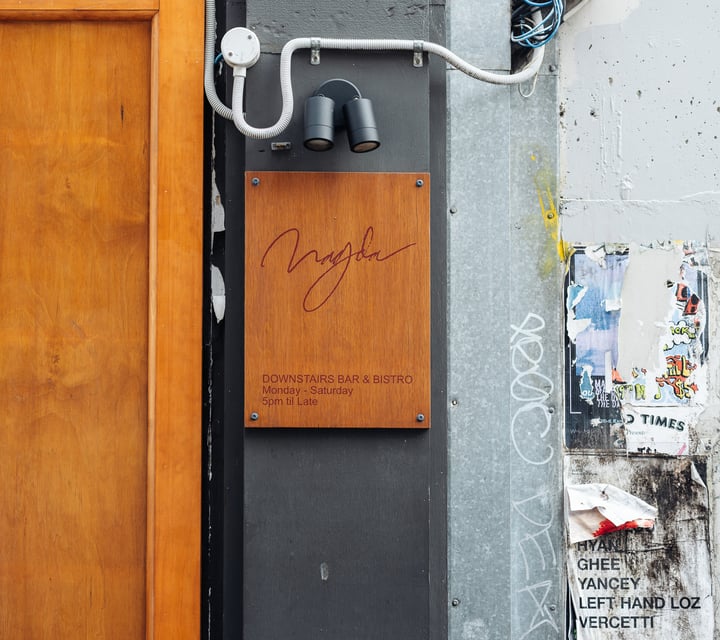 A wooden sign with information on Bar Magda.