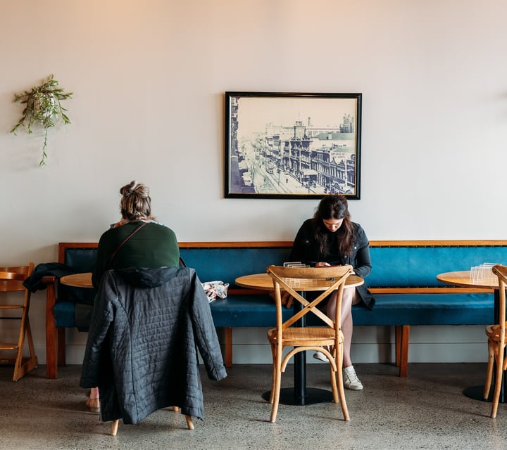 Two customers sitting at tables inside Falafel Metro Tauranga.
