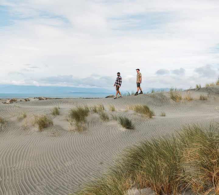 Two men walking along the beach on a sunny day.