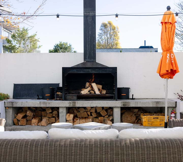 An outdoor fire and white seating at Hotel Montreal in Christchurch on a sunny day.