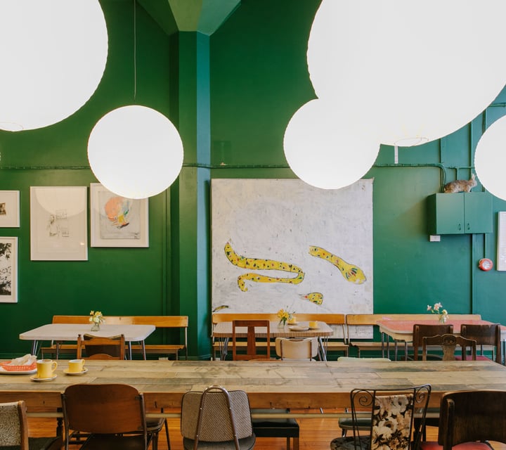 Large tables with low hanging lights set against dark green walls.