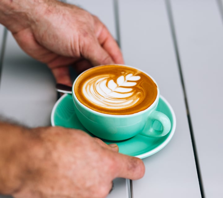 Man puts coffee on table at Manuka Brothers, Hamilton.