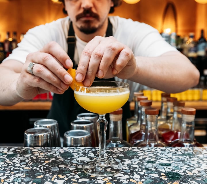 Close up of a bartender garnishing a cocktail.