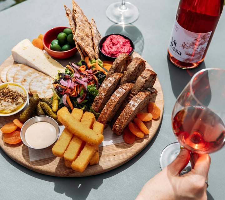 A cheese platter and a glass of rose wine.
