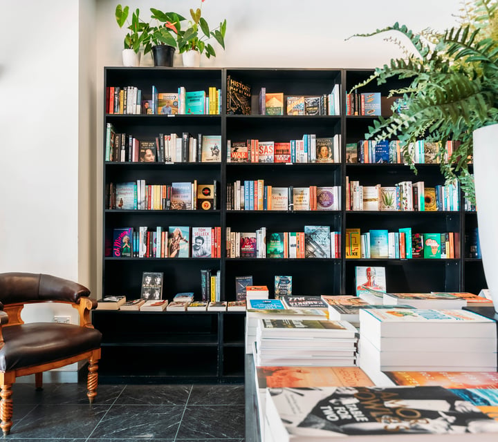 Books on display on a black shelf in a brightly lit bookshop.