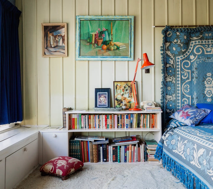 A colourful bookshelf by an old bed in the Ngaio Marsh House.