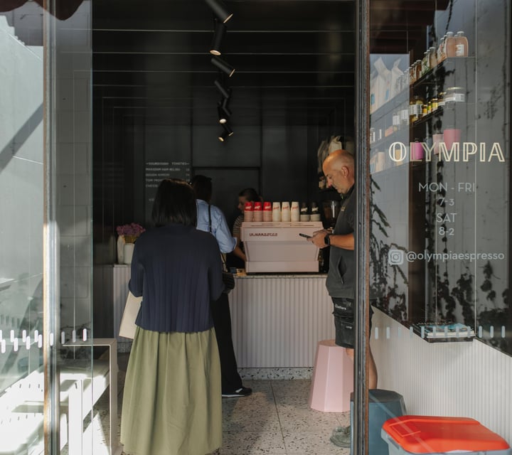 People lining up inside a small cafe.