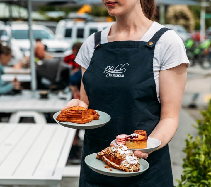 Staff member holding three plates of pastries at Pembroke Pâtisserie.