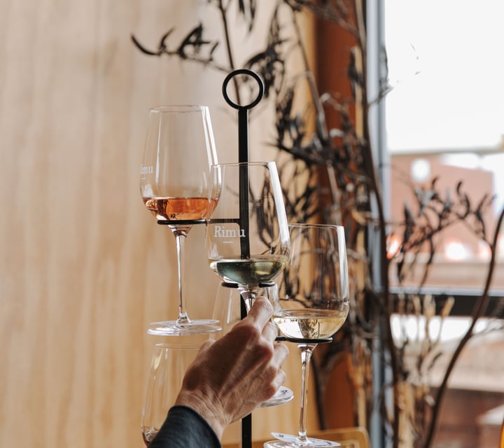 A woman sitting next to three glasses of wine inside Rimu Wine Bar in Mapua.