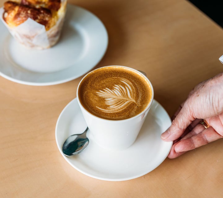 Waiter putting coffee and muffin down on cafe table