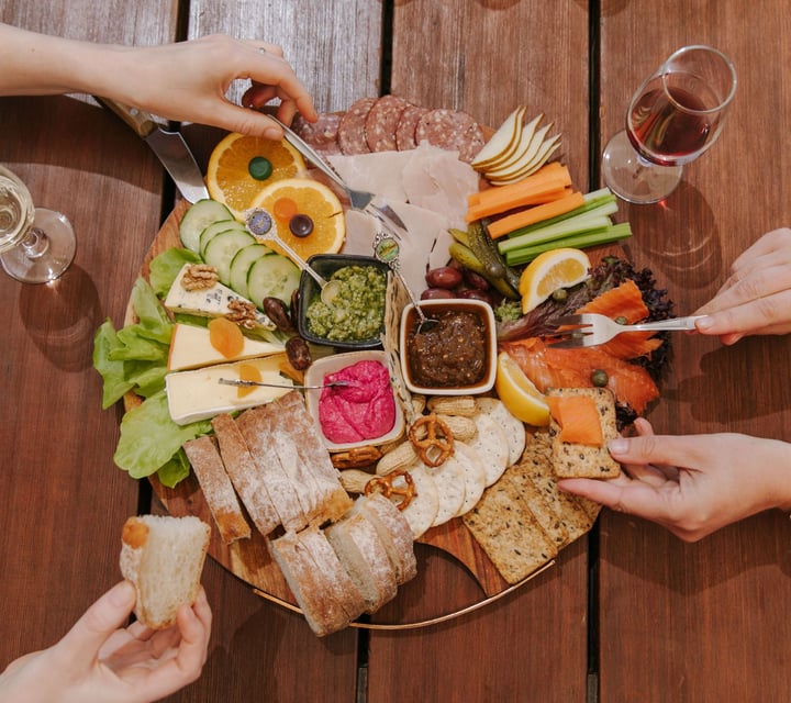 A brids eye view image of a cheese and crackers board with people eating it.