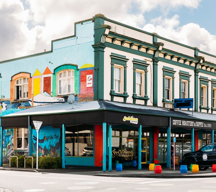 Colourful building exterior of Sublime Coffee Roasters with cars parked outside.