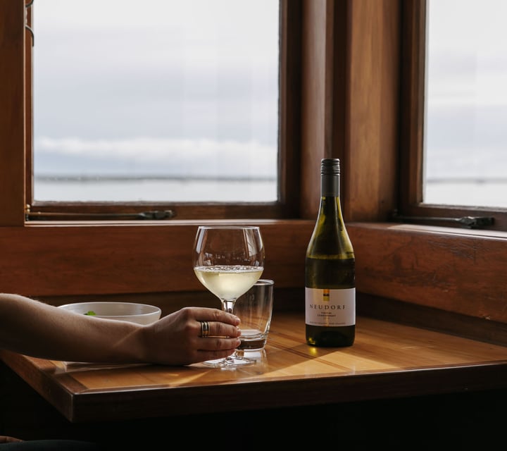 Woman holding a glass of white wine at Boat Shed Cafe.