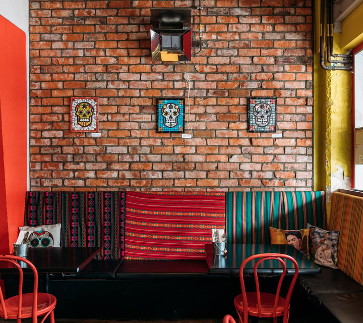 Interior of Mexican restaurant with exposed brick walls, Mexican skull mosaics and Day of the Dead decor