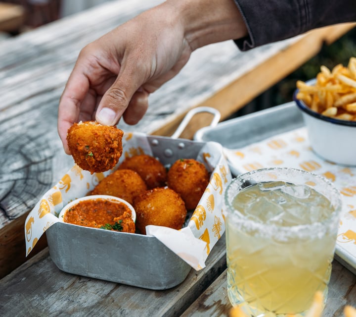 Hands holding a deep fried ball.