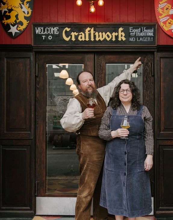 Owners of Craftwork standing outside the building with a pint in hand.