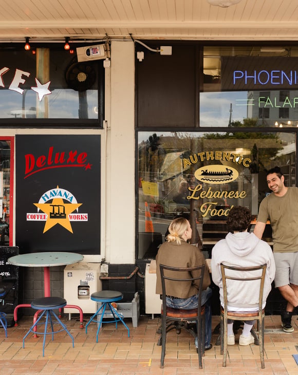 Customers sitting at an outdoor table outside Phoencian Falafel.