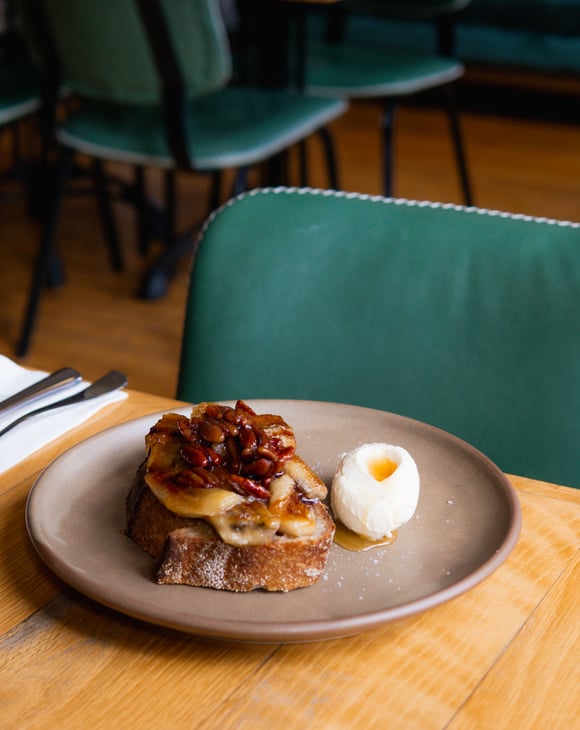 Elevated version of french toast with grilled bananas and a quenelle of cream on the side