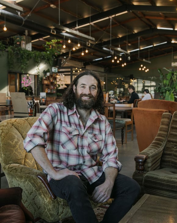 Chef Pedro Johnston sitting on couch smiling at Scoundrel in Christchurch