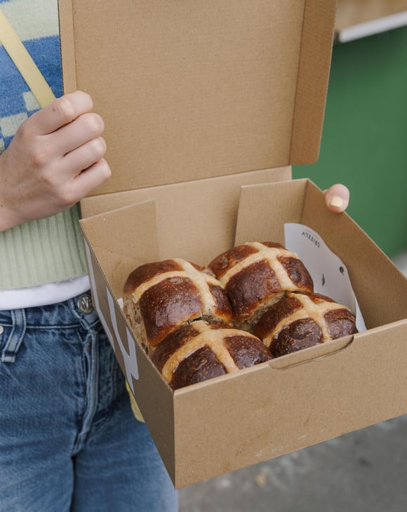 Person holding box of four Hot Cross Buns outside Grizzly in Christchurch