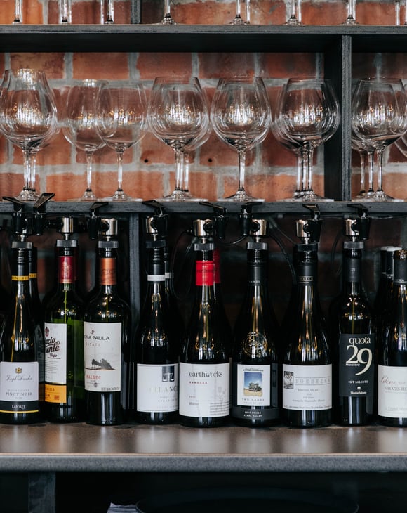 Bottles of red wine lined up in a row on a table.
