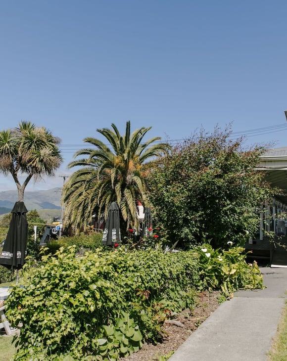 Lush garden area at Ōtoromiro Hotel in Governor's Bay overlooking water and hills