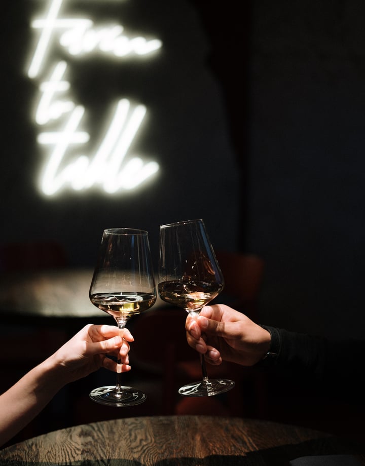 Close up of two hands clinking wine glasses.