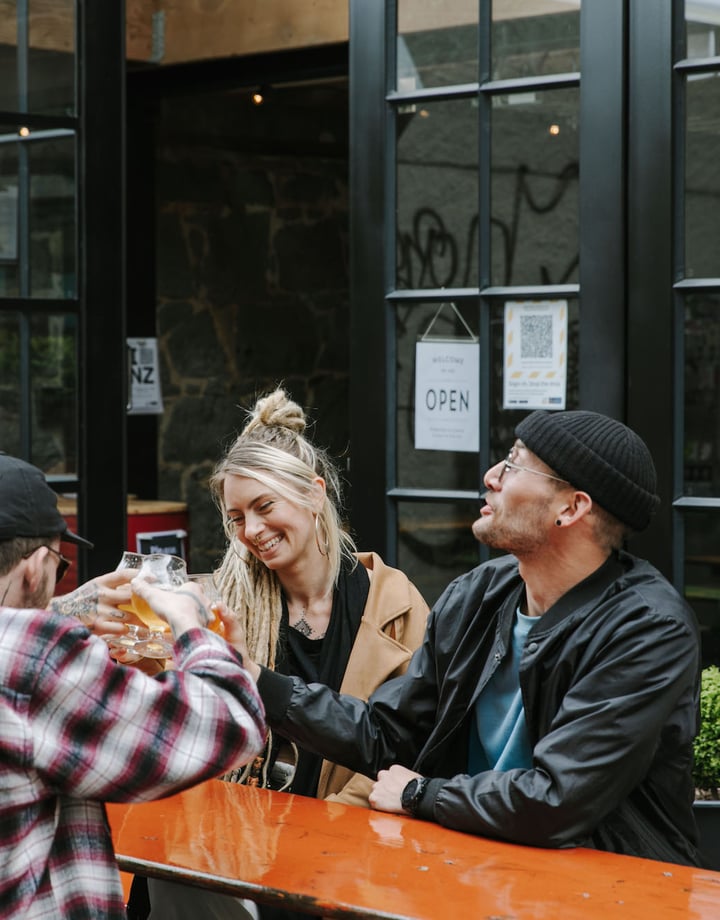 A group of people sat around a table drinking beer at Steamer Basin, Dunedin.