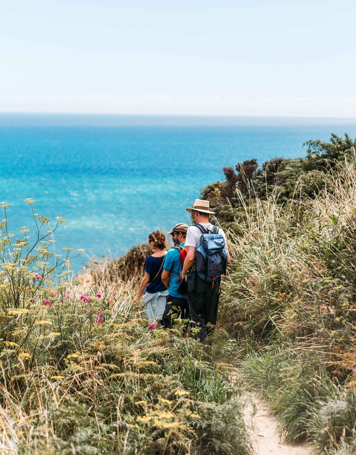 A group of people are walking on a track with the ocean in the background.