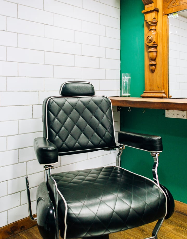 Black barber chair in front of salon mirror at Boar and Blade in Wellington
