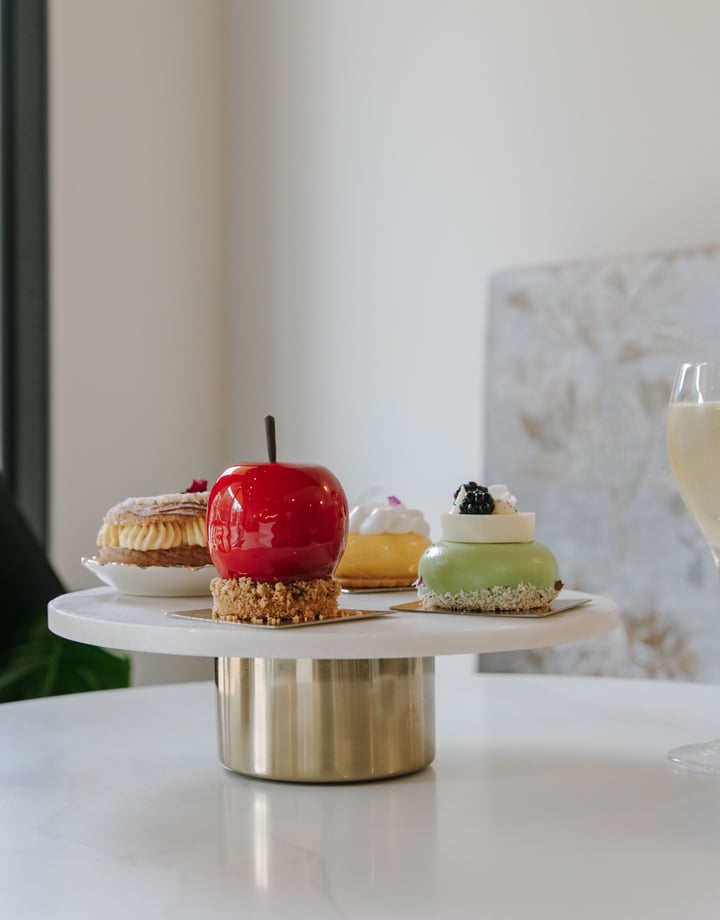 Shiny cakes on a cake stand on a white table.