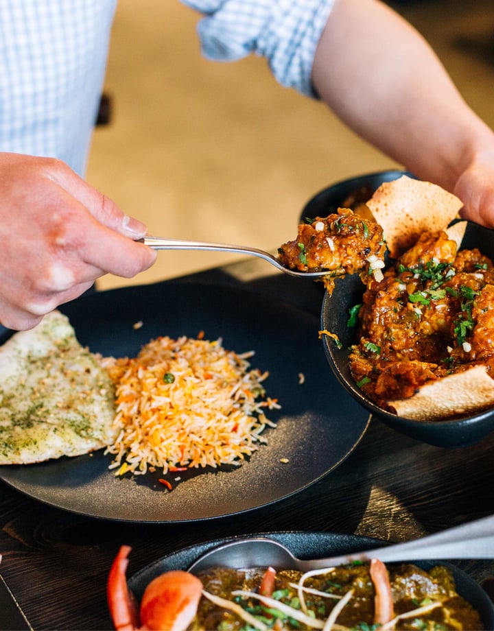 Indian food being scooped onto a plate.