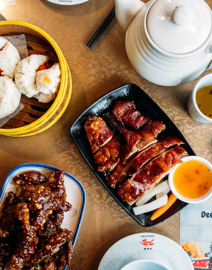 Table full of plates of Asian dishes and chopsticks.