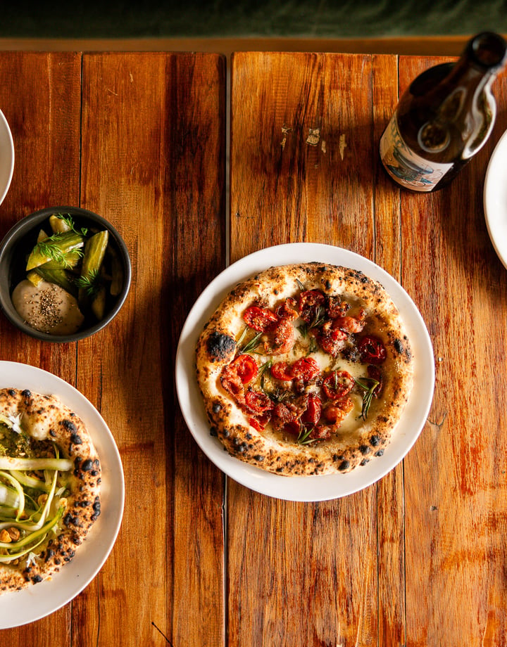 A flatlay of plates of pizza and drinks on a table.