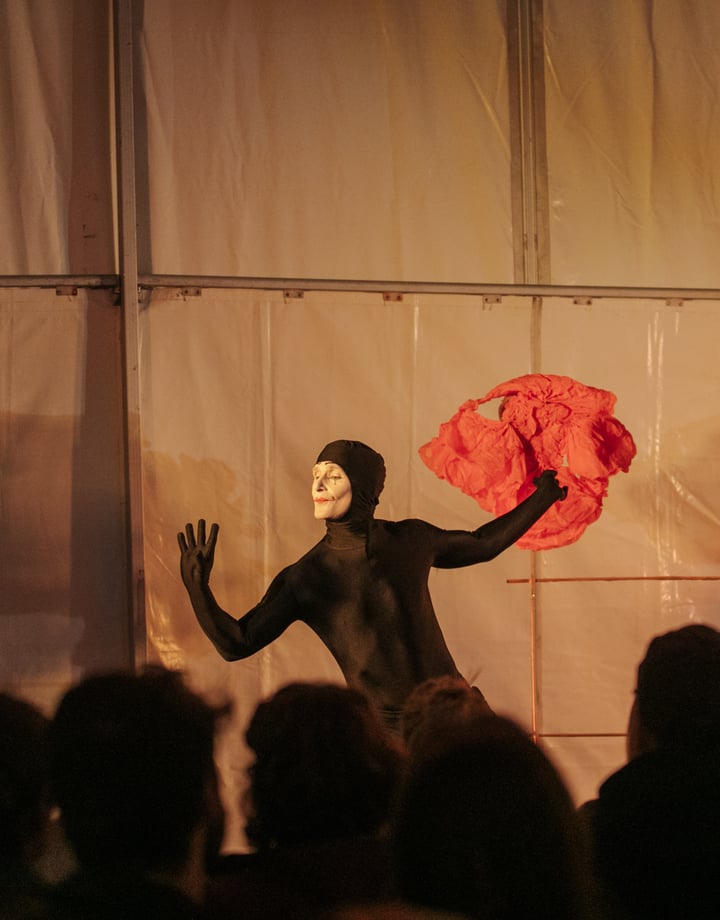 A man dressed in a black holding a red piece of fabric.