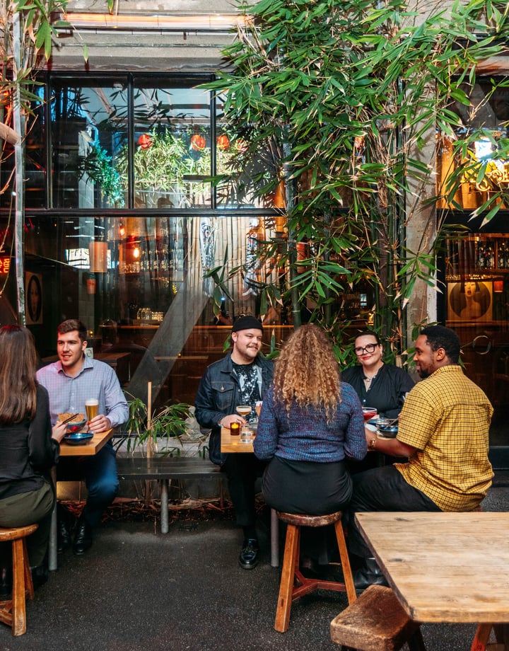 People dining outside by a building covered in vines.