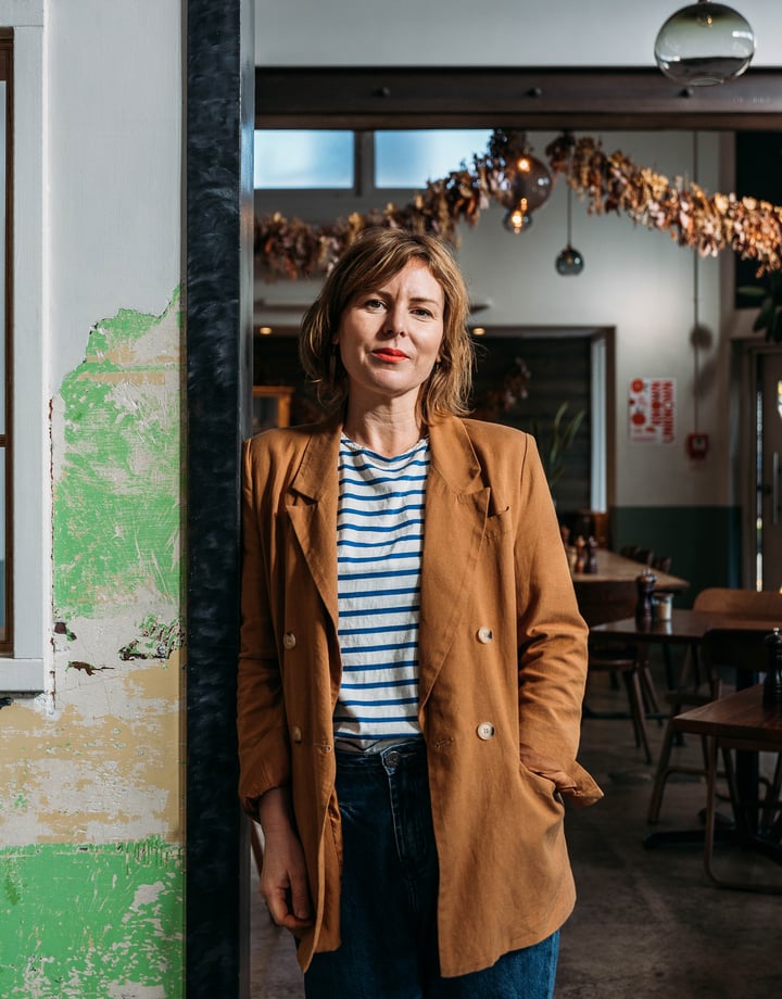 A woman in her cafe posing for the camera.