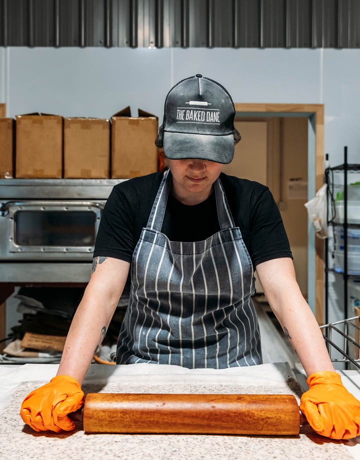 Baker rolling out dough in the kitchen at The Baked Dane.