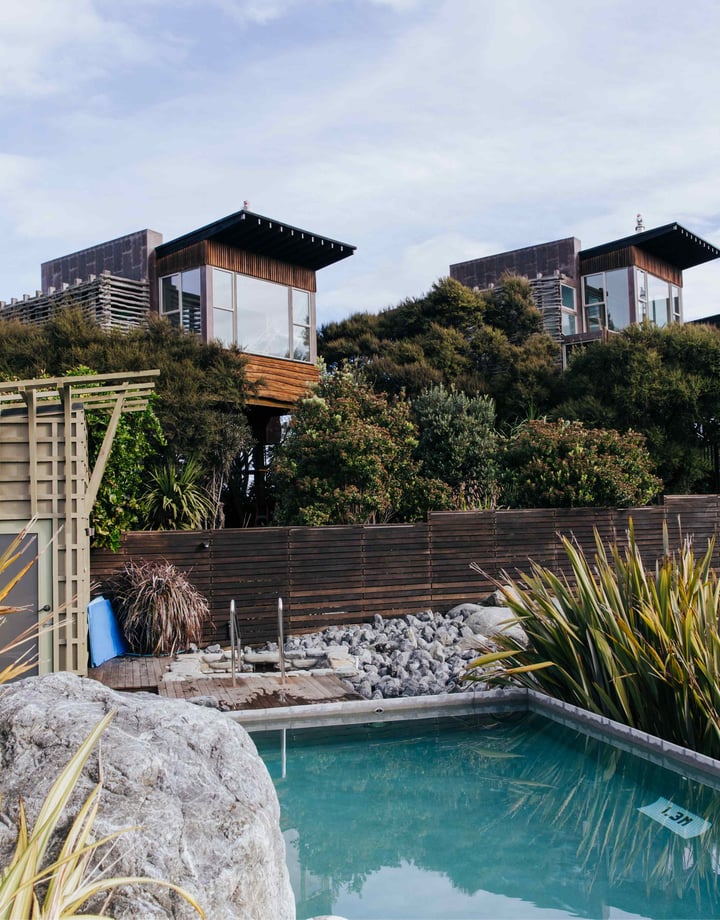 Wooden apartments set behind a swimming pool on a sunny day.