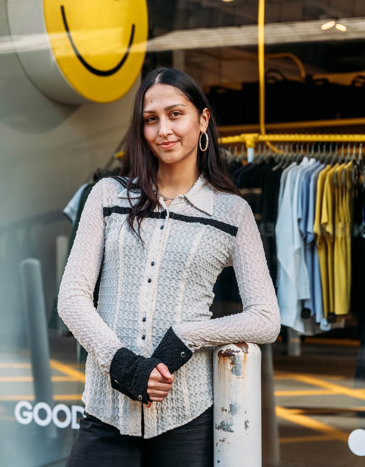A woman wearing black and white standing in front of a clothing store.