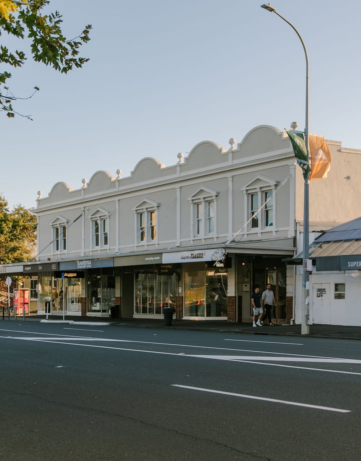 A view of old shops next to the road at dusk.