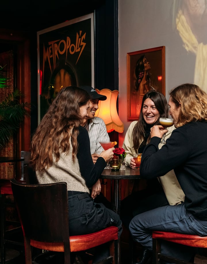 People sitting around in a dimly lit room drinking.