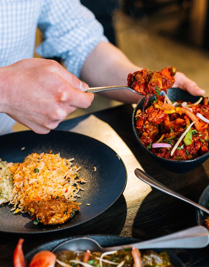 A man's hand serving himself at an Indian restaurant.