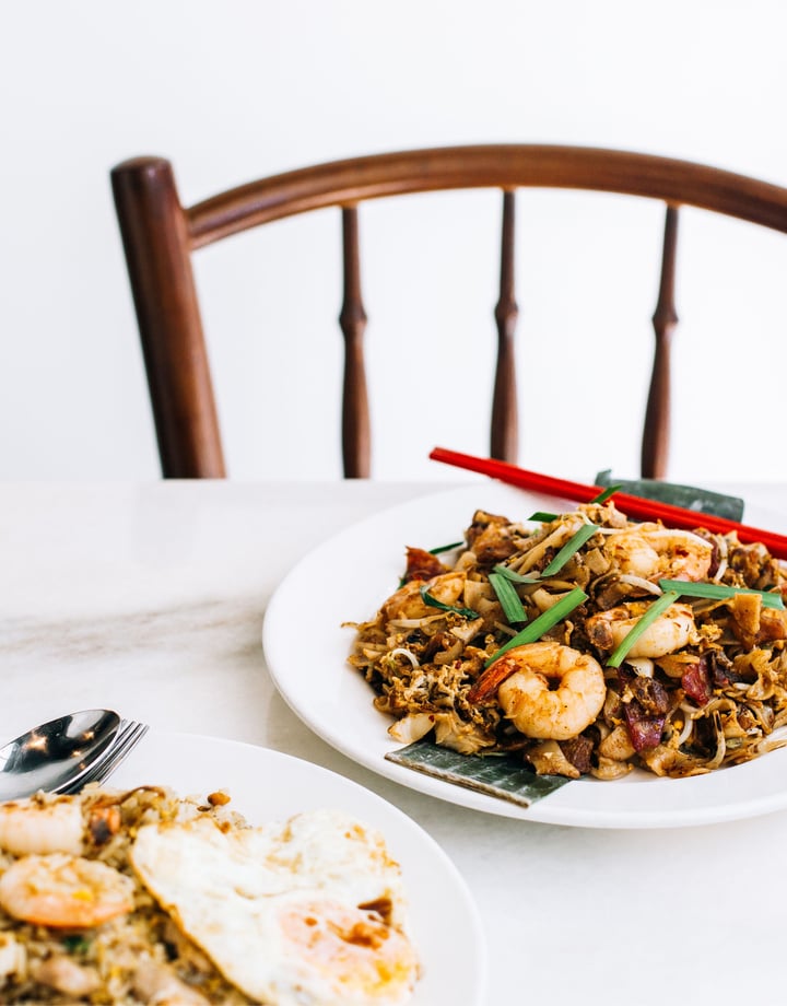 A bowl of noodles and a bowl of fried rice against a white background.