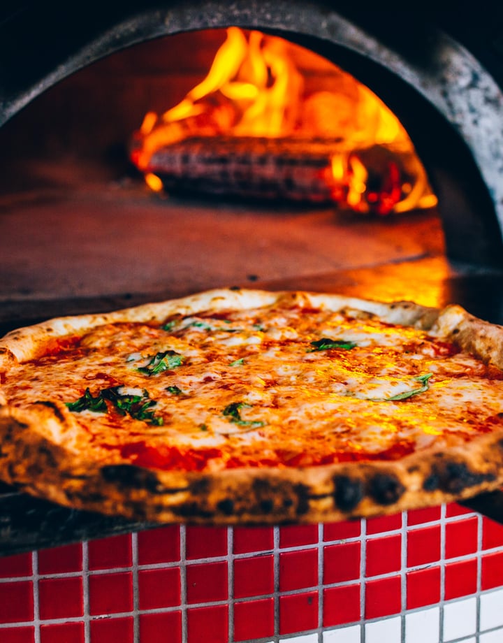 A pizza coming out of a hot oven.