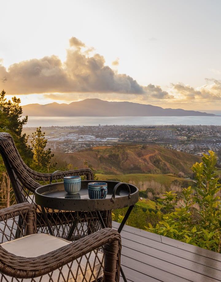 Table and chairs on a balcony overlooking the coastline.