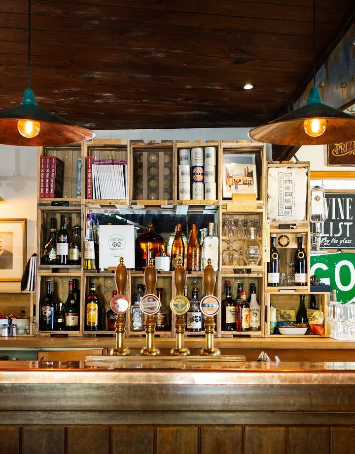 A wooden bar with green downlights where there are 4 beers on tap.